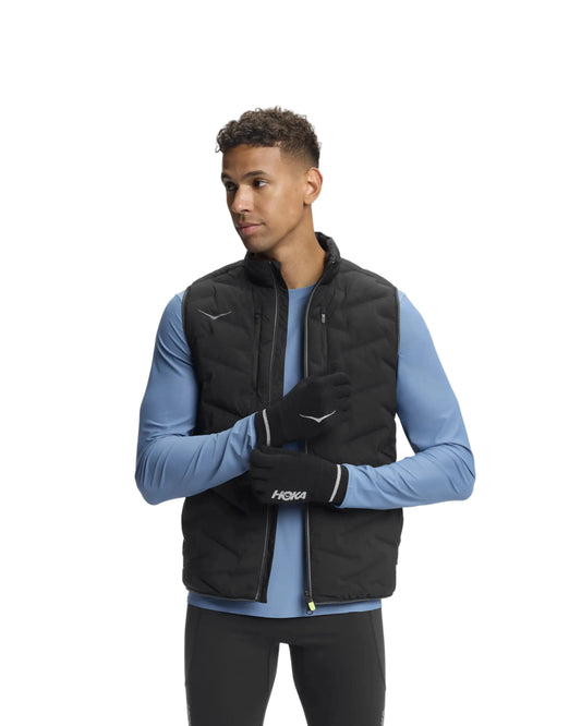 Man wearing a black puffer vest over a blue long-sleeve shirt on a white background