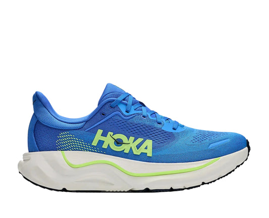 A HOKA running shoe in vibrant blue with a white midsole and neon green accents, shown in a side profile on a light gray background.
