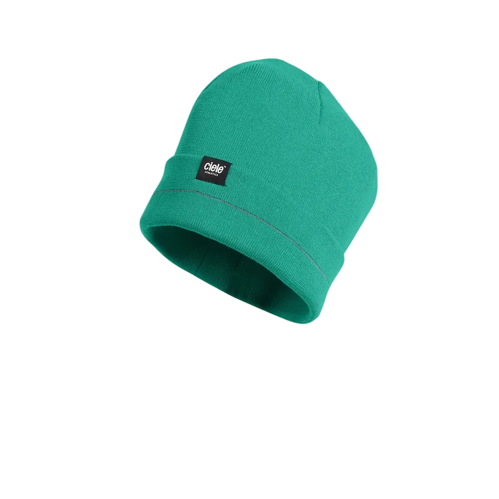 A teal green knit beanie hat with a small black brand patch on the front cuff, shown floating against a light gray background with a soft shadow underneath.