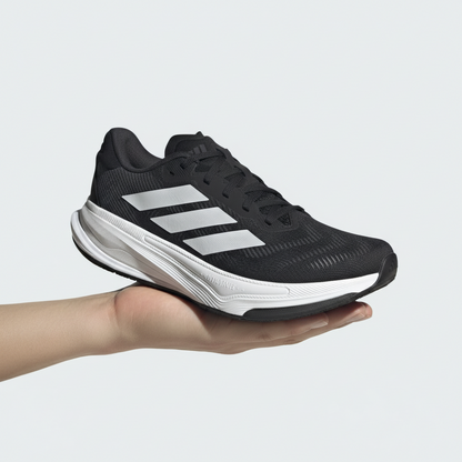 Black Adidas running shoe with white sole on a white background